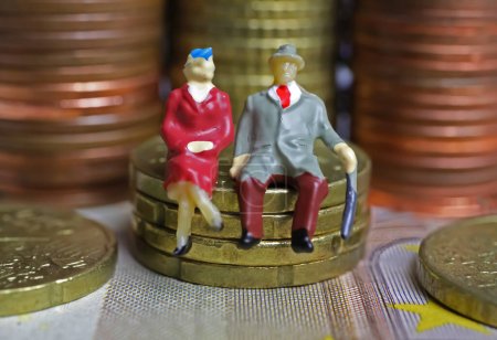 Cifras aisladas abstractas de una pareja de ancianos jubilados sentados en una pila de monedas en euros dinero - concepto de pensiones y ahorros para la jubilación