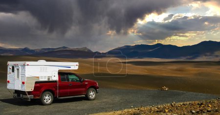 Téléchargez les photos : 4x4 camping-car sur le plateau du point de vue, paysage glacial aride et sec sans fin, changement climatique avec nuages strom sombres - centre de l'Islande - en image libre de droit