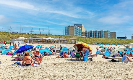 Téléchargez les photos : Zandvoort, Pays-Bas - 9 juin. 2023 : Personnes sur la plage de sable hollandaise le jour ensoleillé, NH Hôtel bord de mer bâtiment fond - en image libre de droit