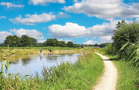 Foto de Hermoso paisaje rural holandés, río Aa con remos de pie, senderismo junto al río vacío y carril bici - Heeswijk, Noord-Brabant, Países Bajos - Imagen libre de derechos