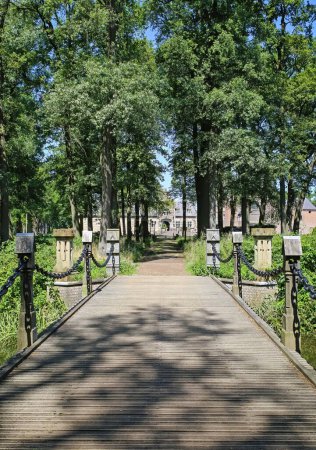 Téléchargez les photos : Belle randonnée pédestre et piste cyclable sur le pont à travers la forêt verte au château médiéval hollandais Kasteel Heeswijk, Brabant-Septentrional, Pays-Bas - en image libre de droit