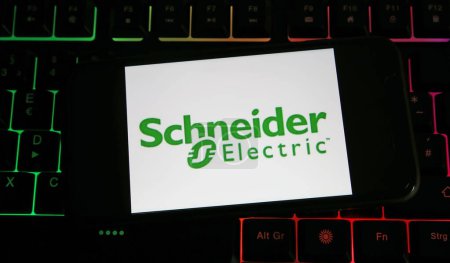 Téléchargez les photos : Viersen, Allemagne - 9 juillet. 2023 : Gros plan de téléphone portable sur clavier d'ordinateur avec lettrage logo de la société Schneider Electric - en image libre de droit