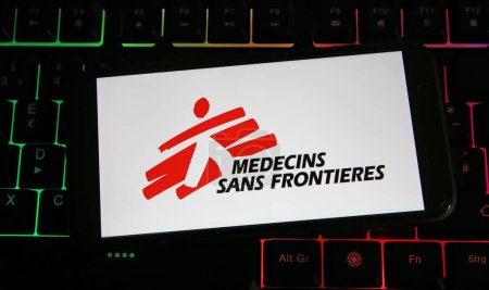 Foto de Viersen, Alemania - 9 de julio. 2023: Primer plano del smartphone con el logotipo de Medecins sin fronteras en el teclado de la computadora - Imagen libre de derechos