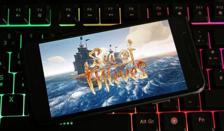 Photo for Viersen, Germany - January 9. 2024: Closeup of smartphone on pc keyboard with logo lettering of Sea of thieves game - Royalty Free Image