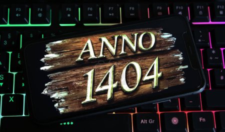 Téléchargez les photos : Viersen, Allemagne - 9 janvier. 2024 : Gros plan de smartphone sur clavier PC avec lettrage logo du jeu Anno 1404 - en image libre de droit