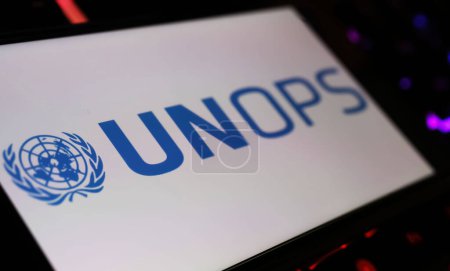 Foto de Viersen, Alemania - 9 de enero. 2024: Pantalla de Smartphone con el logotipo de UNOPS agencia de las naciones unidas en el teclado del ordenador - Imagen libre de derechos