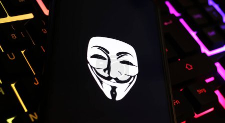 Photo for Viersen, Germany - January 9. 2024: Smartphone screen with Anonymous mask symbol on computer keyboard as cyber attack and hacking concept - Royalty Free Image
