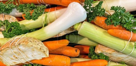 Close up of isolated bundles of fresh raw soup vegetables ingredients on german farmer market: leeks, carrots, celery and parsley