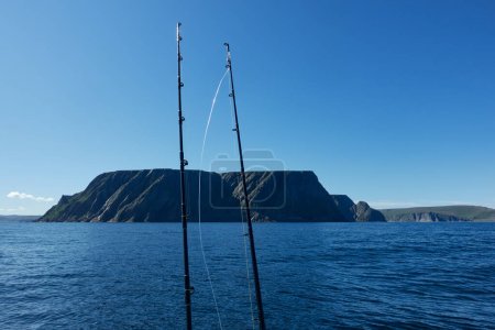 Photo for The northernmost tip of Europe large and dramatic rock cliff of North Cape and two fishing rods on summer day on Mageroya island in Finnmark in Northern Norway. - Royalty Free Image