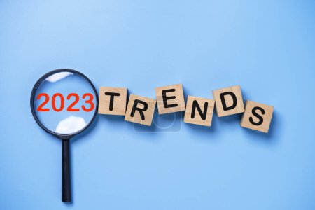 2023 Jahr im Inneren der Lupe mit Trendwortlaut auf blauem Hintergrund für Marketing-Monitor und Geschäftsplanung Fokus ändern Konzept.