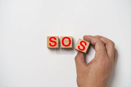 Foto de Hand arrange red SOS signal wording on white background for Save Our Souls concept. - Imagen libre de derechos
