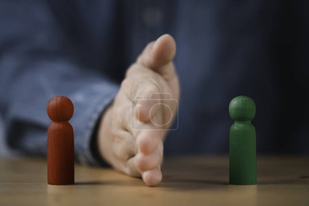 Photo for Palm hand blocking and divide between red and green wooden figure for resolving conflict and mediate management concept. - Royalty Free Image