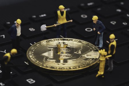 Mineros figuras en miniatura minería bitcoins de oro en el teclado de la computadora para el comercio de inversión criptomoneda por concepto de tecnología de cadena de bloques