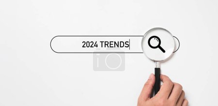Photo for Hand holding magnifier glass with 2024  trends  searching bar for optimization 2024 business marketing trends and planing change concept. - Royalty Free Image