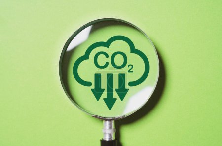 Lupa con reducción de CO2 sobre fondo verde para reducir el CO2, la huella de carbono y el crédito de carbono para limitar el calentamiento global por el cambio climático en el concepto del Protocolo de Kyoto 2050.