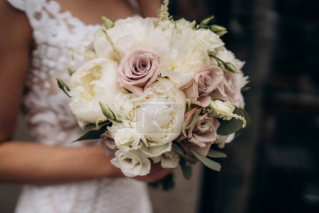 Schöne Braut hält weißen Strauß. Strauß aus weißen Rosen in Frauenhänden