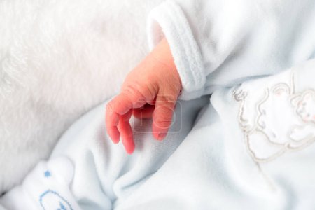 El primer plano de una mano de un recién nacido con ropa blanca