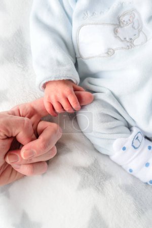 Close up of a hand of a newborn with white clothes