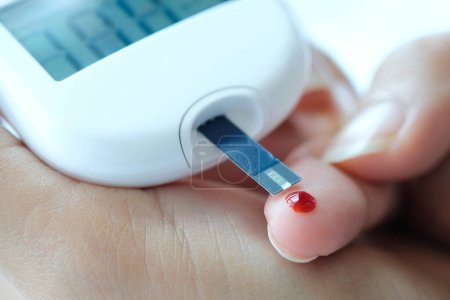 Die Hand der Menschen überprüft Diabetes und hohen Blutzuckerspiegel mit einem digitalen Druckmessgerät. Gesundheitswesen und medizinisches Konzept