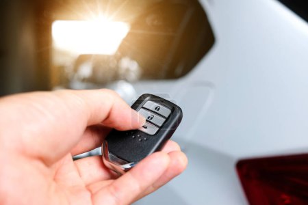 Photo for Man hand holding the car remote, he push the remote control to open the car door - Royalty Free Image