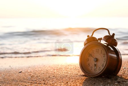 Morning of a new day, alarm clock on the beach sunlight in morning. Health and holiday concept.