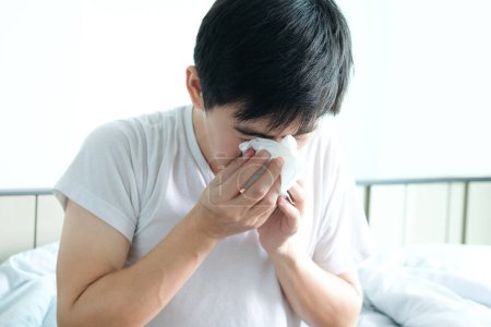 Foto de El enfermo es gripe, usa una servilleta de papel y tiene secreción nasal. Y estaba cubierto de ropa abriga.Concepto de salud - Imagen libre de derechos