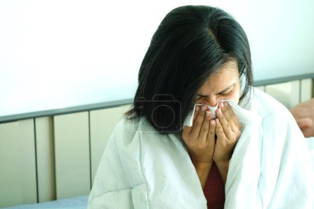 Foto de La mujer enferma es gripe, usa una servilleta de papel y tiene secreción nasal. Y estaba cubierto de ropa abriga.Concepto de salud - Imagen libre de derechos