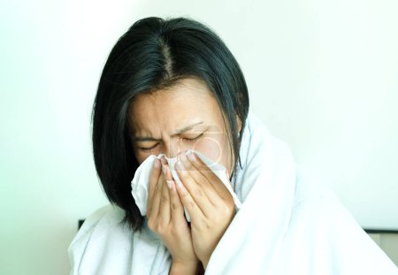 Foto de El enfermo es gripe, usa una servilleta de papel y tiene secreción nasal. Y estaba cubierto de ropa abriga.Concepto de salud - Imagen libre de derechos