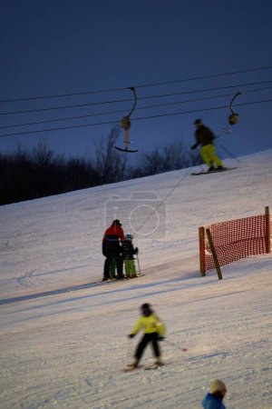 Téléchargez les photos : Treffelhausen, Germany - January 28, 2022: Ski drag lift in operation at night with lighting. Winter athletes on the slopes in the snow. Long exposure, blurred. - en image libre de droit