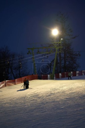 Photo for Treffelhausen, Germany - January 28, 2022: Ski drag lift in operation at night with lighting. Winter athletes on the slopes in the snow. Long exposure, blurred. - Royalty Free Image