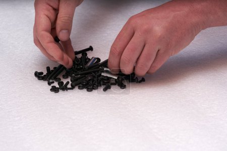 Téléchargez les photos : 2 hands searching black screw on a bolt heap. Connecting elements for industry and crafts. - en image libre de droit