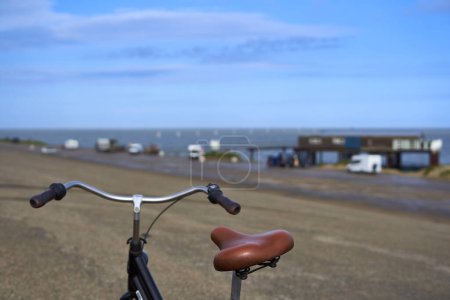 Bicicleta en frente de casa de playa en Holanda. Amanecer en la presa. Restaurante y autocaravanas junto al mar. Ciclismo en Holanda, Zelanda, Schouwen Duiveland.