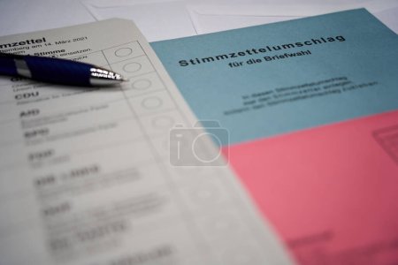 Deutsche Stimmzettel mit blauem Stift. (Übersetzung des Wortes Briefwahl). Umschlag als Symbol der Briefwahl in Demokratien.
