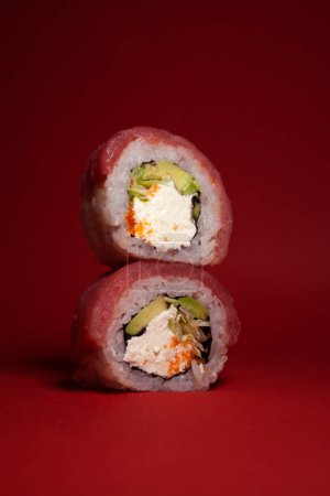 Foto de Rollos de sushi de atún con aguacate verde y queso sobre fondo rojo - Imagen libre de derechos