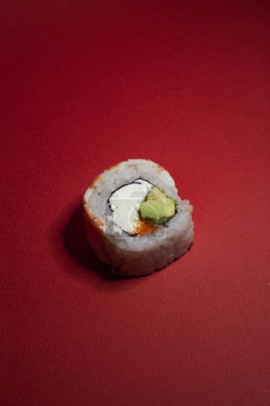 Foto de Rollo de sushi de camarones con aguacate verde y queso sobre fondo rojo - Imagen libre de derechos