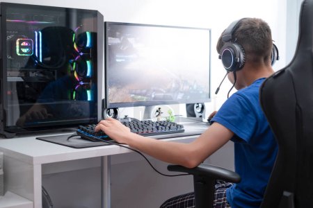 Téléchargez les photos : Un adolescent joue à des jeux vidéo sur un ordinateur de jeu, dépendance aux jeux vidéo à l'adolescence, mise au point sélective - en image libre de droit