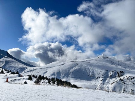 Photo for Ski slopes of a winter resort, on a blue sky day with big cotton clouds behind the mountains, Cerler, Huesca, Spain, horizontal - Royalty Free Image