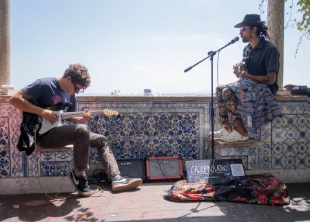 Photo for Two street musicians play guitar for tourists at the mirador de santa lucia, in the Alfama district of lisbon, Portugal, horizontal - Royalty Free Image