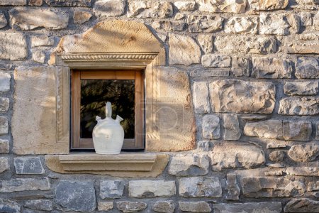 Photo for A white botijo on the exterior window sill of a stone village house, typical spanish clay jug to keep the water cool in summer, rustic atmosphere - Royalty Free Image