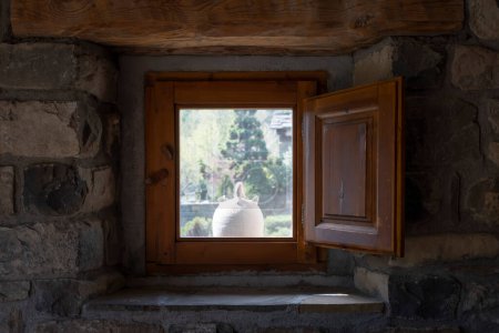 Photo for A white botijo seen from the inside of a window of a stone village house with wooden shutters, typical spanish clay botijo to keep the water cool in summer, rustic atmosphere, horizontal - Royalty Free Image