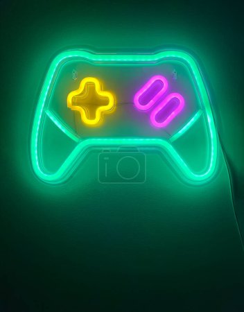 Photo for Led lights imitating neon lights in the shape of a video game console controller in green, yellow and pink, gaming set, vertical - Royalty Free Image