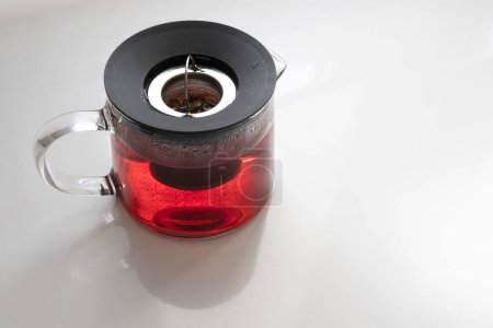 a glass teapot with a fruit infusion, infuser pitcher with a strawberry infusion, red tea, apple or berry infusion on a white table, copy space, horizontal