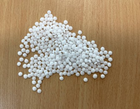 Photo for A pile of white pellets on a wooden table, production of plastic parts, plastic injection, a bunch of plastic pelets, plastic grains, horizontal - Royalty Free Image