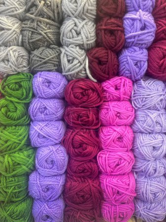 ball of wool of different colours stacked in rows, haberdashery, wool and sewing supplies shop, vertical