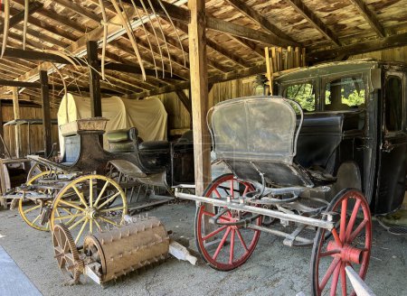 Historic carriage house interior in the recreated and restored 1800 Pioneer Village at Spring Mill State Park, near Mitchell, Indiana with wagons and carriages.