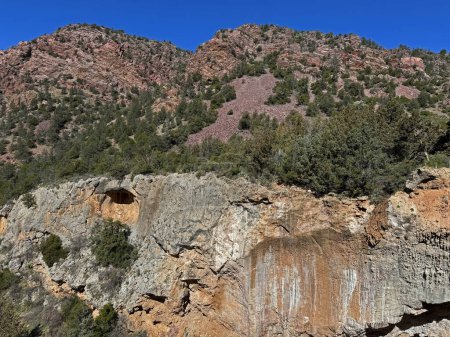 Foto de Vista primaveral del paisaje rocoso rojo de la montaña en el Parque Estatal Tonto Natural Bridge en Pine, Arizona con espacio para copiar el cielo azul brillante en un área por encima del puente natural. - Imagen libre de derechos