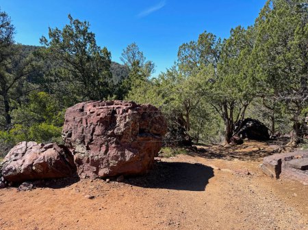 Springtime view of a large boulder beside the Gowan hiking trail in Tonto Natural Bridge State Park in Pine, Arizona with bright blue sky copy space in an area above the natural bridge.