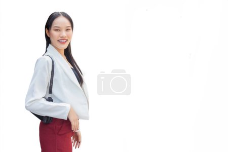 Young Asian business working woman wear white suit and red pants smiling carry bag while walking in the city while isolated white background.