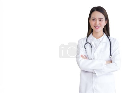 Foto de Joven asiática profesional médico de pie con los brazos cruzados vistiendo bata blanca y estetoscopio en la sala de examen en el hospital mientras aislado fondo blanco. - Imagen libre de derechos