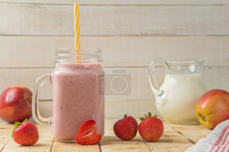 Photo for Fresh milkshake with strawberries. A glass of fresh strawberry milkshake. Fresh strawberry puree on a light wooden background. Healthy food and drink concept - Royalty Free Image